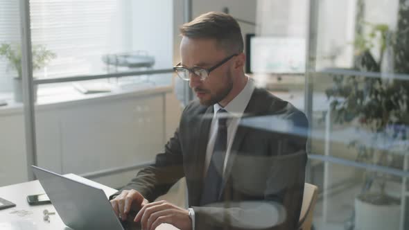 Businessman Using Laptop at Desk in Office