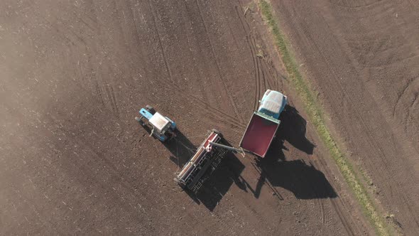 Aerial View of Tractor with Mounted Seeder Performing Direct Seeding of Crops on Plowed Agricultural