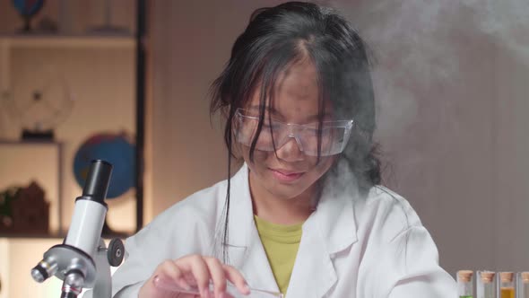 Asian Scientist Girl With Dirty Face Mixing Chemical Liquids In Flasks. Child Learn With Interest