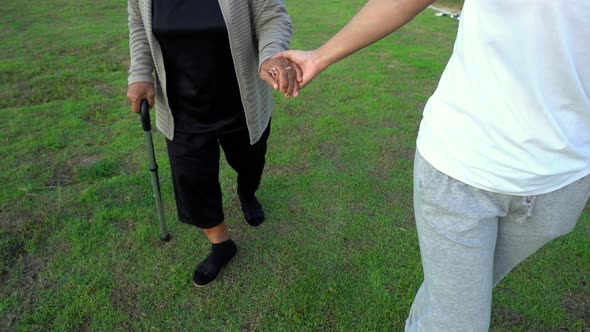 slow-motion of woman hold hands of elderly woman and walking in the park