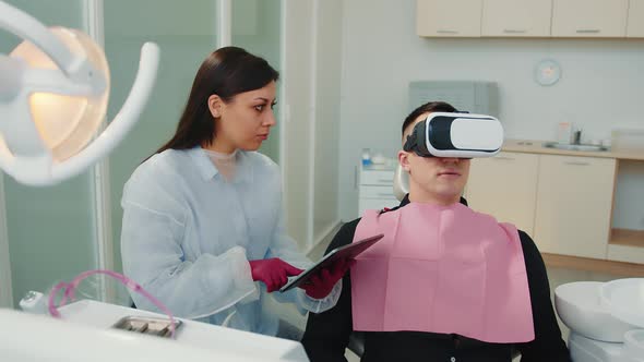 The Dentist Demonstrates to the Patient in VR Glasses of Dental Treatment and the Appearance of New