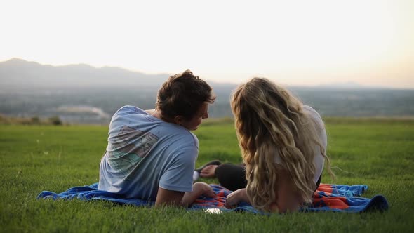 Slow Motion shot of cute boyfriend and girlfriend laying on a blanket and having a picnic on the gra