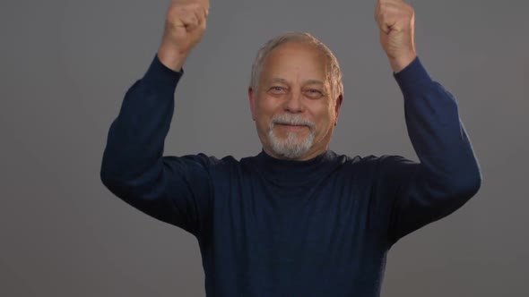 Excited Senior Man Raises Hands and Shakes Showing Thumb-up