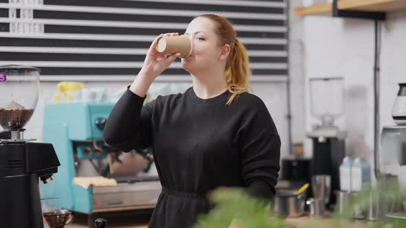 Middle Shot of Smiling Charming Plussize Caucasian Woman Drinking Coffee From Disposable Cup