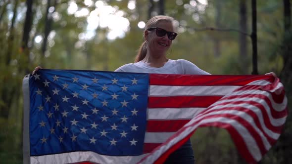 Closeup of pretty blonde woman dancing with an American flag and spinning it around her.