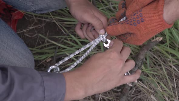 Top View of Two Workers Unscrewing a Bolt That Holds a Cable Construction