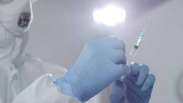 Hands of Doctor in Protective Gear Flicking Syringe