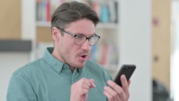 Middle Aged Man Excited By Success on Smartphone