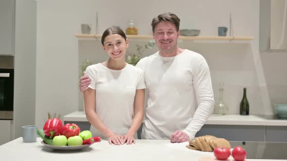 Mixed Race Couple Smiling at Camera in Kitchen