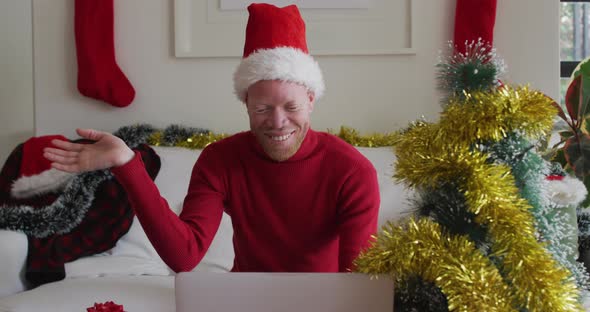 Happy albino african american man wearing santa hat making video call at christmas