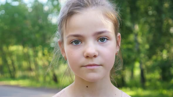 Schoolgirl Stands on Blurry Green Forest Pathway Closeup