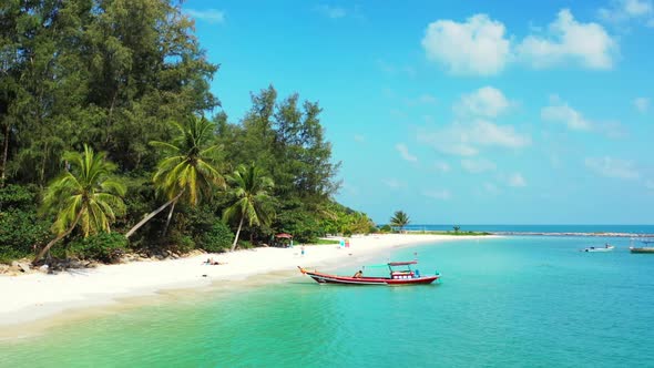 Aerial drone shot seascape of idyllic island beach holiday by shallow water with white sand backgrou