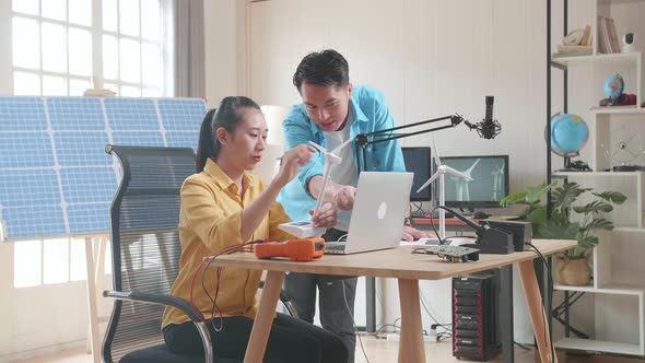 Asian Man And Woman Discuss About Work With Wind Turbine And Laptop Computer