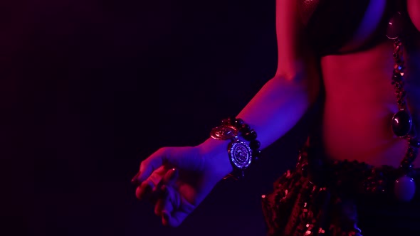 Closeup of the Body of a Woman Dancing an Oriental Dance in a Smoky Studio Against a Dark Background