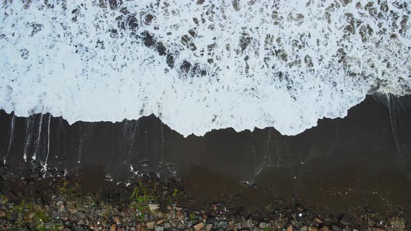 waves wahing beach top view exture black sand india mumbai movie lef drone shot .