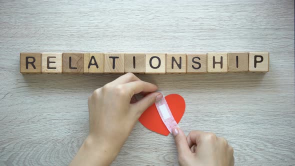 Relationship Word on Wooden Cubes, Female Hands Putting Patch on Paper Heart