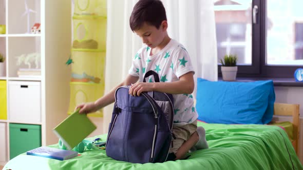 Boy Packing Schoolbag with School Supplies at Home 13