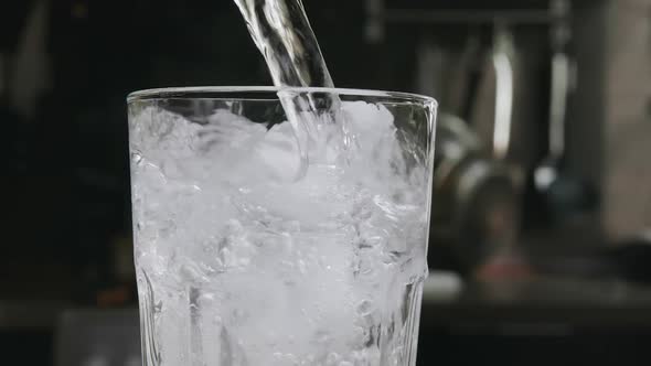 Water Pouring Into a Glass with Ice Cubes