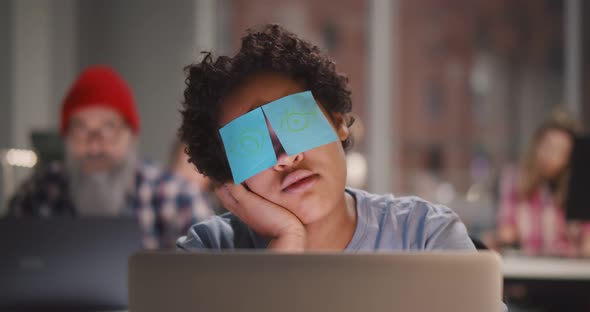 Tired African Woman Sleeping at Workplace with Stickers on Eyes