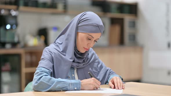 Young Arab Woman Writing on Paper at Work 