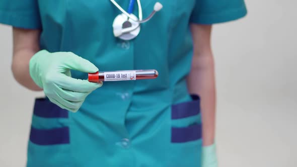 Medical Doctor Nurse Woman Wearing Protective Mask and Latex Gloves - Holding Blood Test Tube