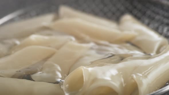 Scooping cooked penne pasta out of water. Slow Motion.