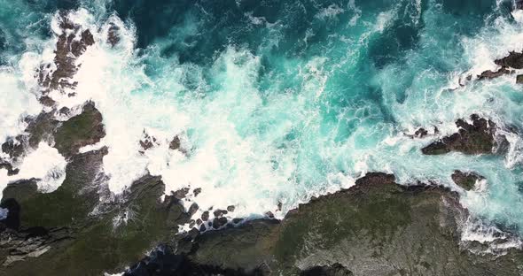 Static overhead shot of strong sea waves of Indian Ocean hitting boulder and coral reef in the beach