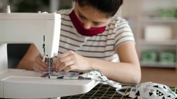 Handheld video of Asian woman sewing protective masks 