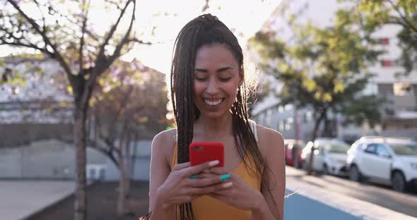 Bohemian mixed race young woman using smartphone outdoor with city in background