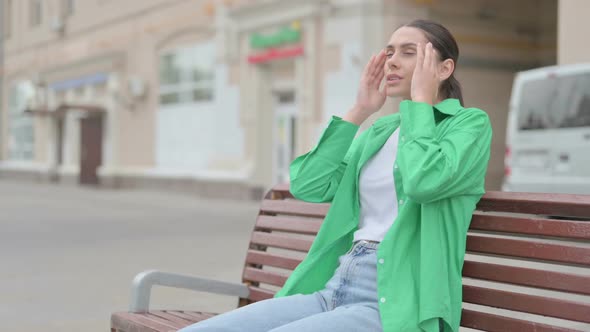 Hispanic Woman with Headache Sitting Outdoor on Bench