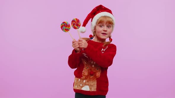 Joyful Girl in New Year Sweater Holding Candy Striped Lollipops Hiding Behind Them Fooling Around