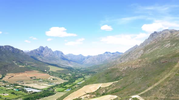 Aerial drone of green and brown farmland valley between mountains with hiking, Stellenbosch, Hottent