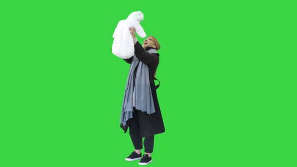 Mom Tosses Up Her Baby in Winter on a Green Screen, Chroma Key.