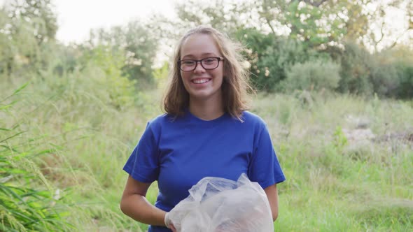 Caucasian woman smiling and looking at camera during river clean-up day