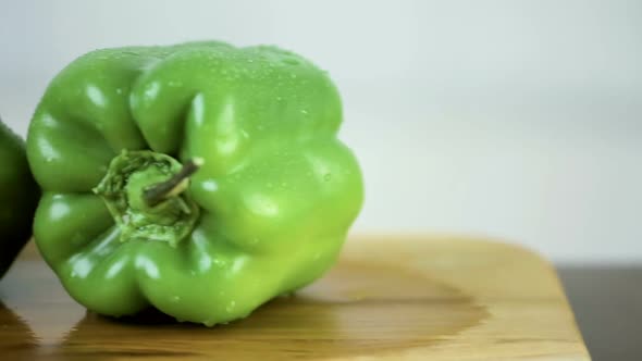 Slicing green bell pepper on a wood cutting board.