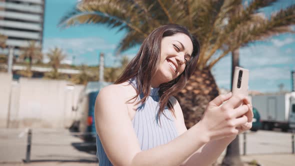 Laughing brunette woman talking by video call on phone