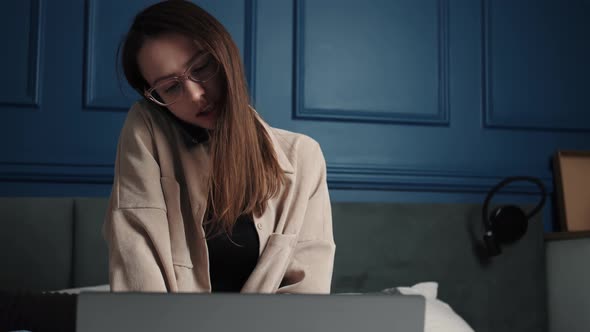 A Woman Talking To Someone on the Phone While Working with a Laptop From Home. Slow Motion