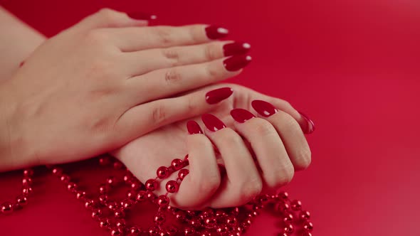 From Above of Crop Anonymous Woman with Red Beads and with Red Manicure on Red Background in Studio