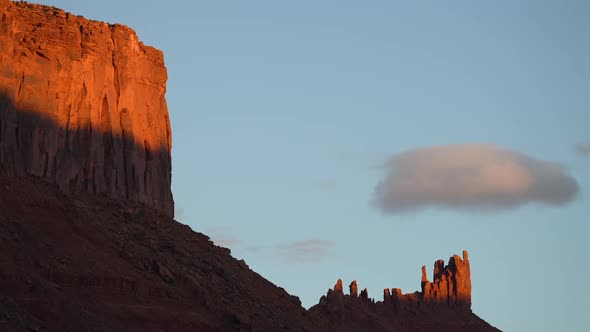 Desert cliffs lit up as clouds move through the sky