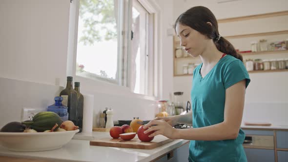 Teenage girl working cutting fruit for breakfast in the kitchen