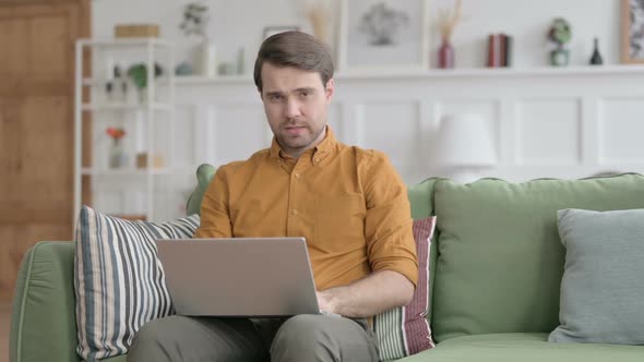 Young Man Shaking Head as No Sign while using Laptop in Office