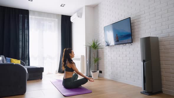 Woman Watching Yoga Tutorial and Sitting in Lotus Pose