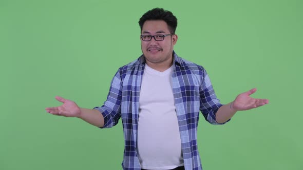 Confused Young Overweight Asian Hipster Man Shrugging Shoulders