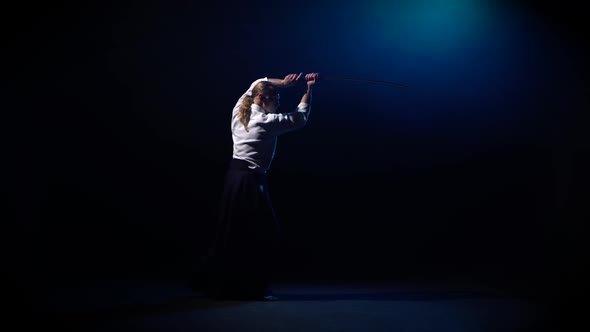 Aikido Master Technique Demonstration with Japanese Sword Katana on Blue Smoke Background.