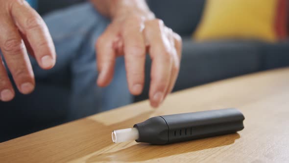 Man with Parkinson's disease using medical Cannabis in vaporizer to stop shaking