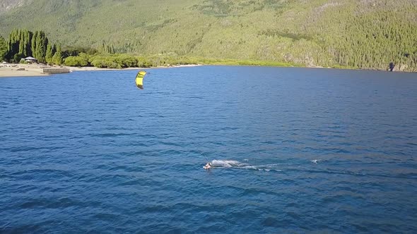 Aerial slow motion of a person practising kitesurf in Puelo Lake, mountains in background, Patagonia