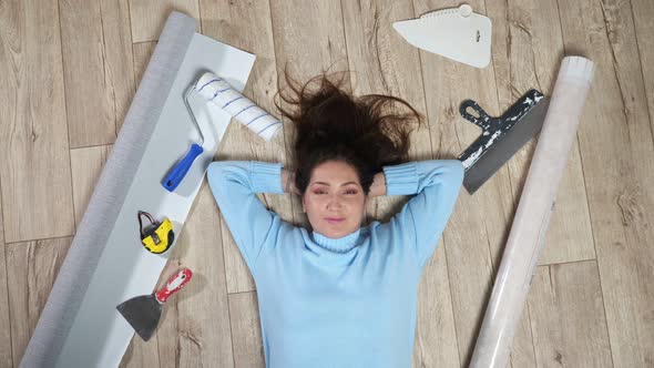 Woman Lies on Floor Among Scattered Building Materials