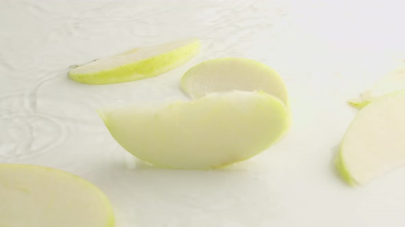 Apples and Slices Falling on White Background with Water