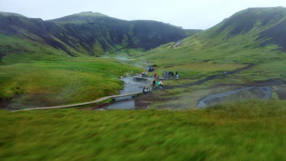 Aerial - Tourists Swimming in a Steamy, hot water mountain river in Reykjadalur Valley - Iceland