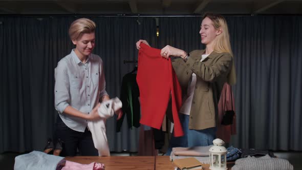 Young Women Second Hand Shop Workers Sort Clothes on Table